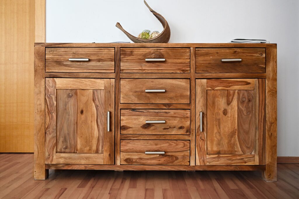 Ein hüfthoher Schrank aus Massivholz mit mehreren Schubläden und zwei Türen.